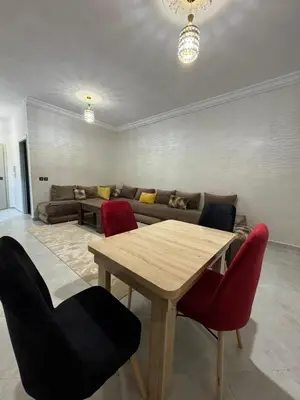 a living room with a wooden table and red chairs at Appartement équipé