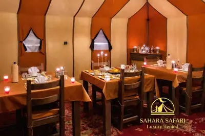 a dining room with tables and chairs in a tent at Sahara Safari Luxury Tented in Merzouga
