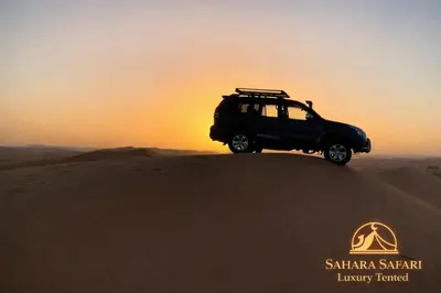 a suv on top of a sand dune in the desert at Sahara Safari Luxury Tented in Merzouga