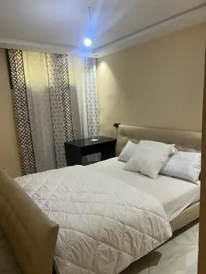 a bedroom with a large white bed and a desk at Cures & détente Appartement moderne Université EUROMED in Fès