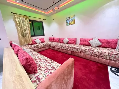 a large couch in a living room with a red carpet at Premium comfort Appartemment lumineux proche médina in Fès