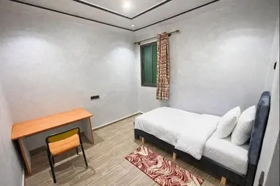 a bedroom with a bed and a table and a window at Premium comfort Appartemment lumineux proche médina in Fès