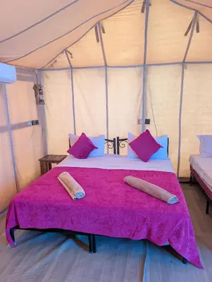 a bed in a tent with two pillows on it at Berber Dreams Desert Camp in Merzouga