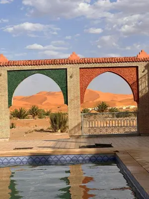 an archway over a pool of water in the desert at Berber Dreams Desert Camp in Merzouga