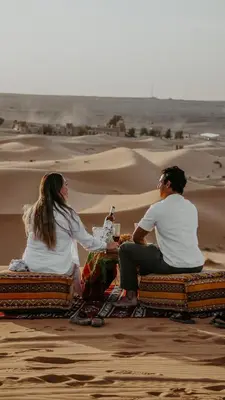 two people sitting on mats in the desert at Berber Dreams Desert Camp in Merzouga