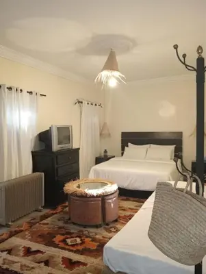 a bedroom with two beds and a tv and a tub at Dar Tissila in Marrakech