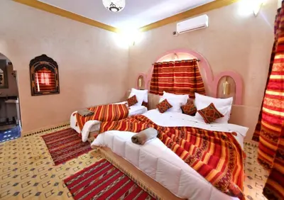 a hotel room with three beds and a window at Riad Ali El Cojo in Hassilabied