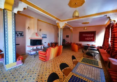a room with chairs and tables and a fireplace at Riad Ali El Cojo in Hassilabied