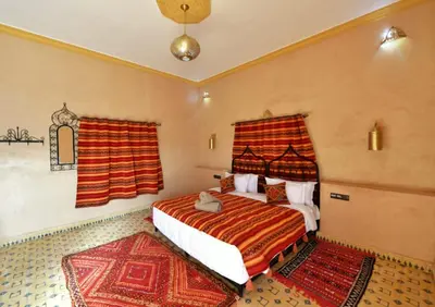 a bedroom with a bed and two rugs at Riad Ali El Cojo in Hassilabied