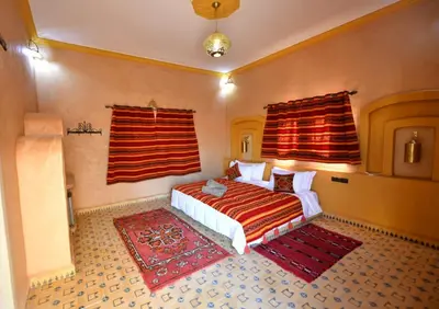 a bedroom with a bed and two red curtains at Riad Ali El Cojo in Hassilabied
