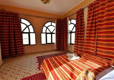a cat laying on a bed in a room with windows at Riad Ali El Cojo in Hassilabied