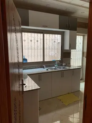a kitchen with white cabinets and a sink and windows at Nice apartment in Fès