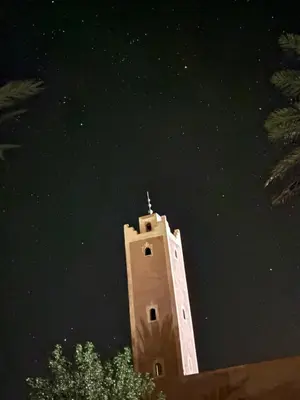 a building with a cross on top of it at night at Zaouit the officialle in Ouarzazate