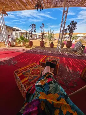 a person laying on a bed with their feet on it at Noor Dunes Camp in Merzouga
