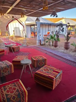 a group of tables and chairs on a red carpet at Noor Dunes Camp in Merzouga