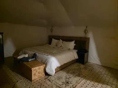 a bedroom with a large bed with white sheets and pillows at Noor Dunes Camp in Merzouga