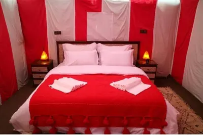 a red and white bed with two white towels on it at Merzouga Luxury Tented in Merzouga