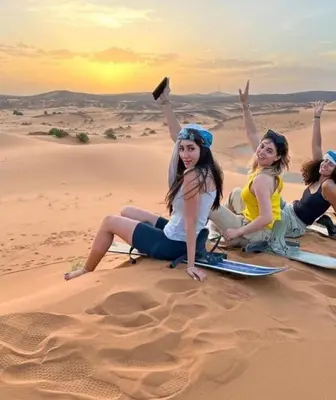 a group of women sitting in the desert at Merzouga Luxury Tented in Merzouga