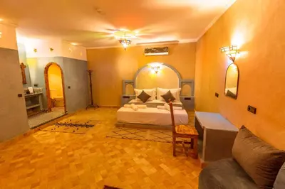 a bedroom with a bed and a living room at Hotel Sunset palace Merzouga in Merzouga