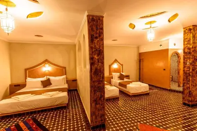 a hotel room with two beds and a bathroom at Hotel Sunset palace Merzouga in Merzouga