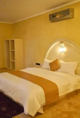a bedroom with a large white bed in a room at Hotel Sunset palace Merzouga in Merzouga
