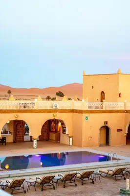 a large swimming pool in front of a building at Hotel Sunset palace Merzouga in Merzouga
