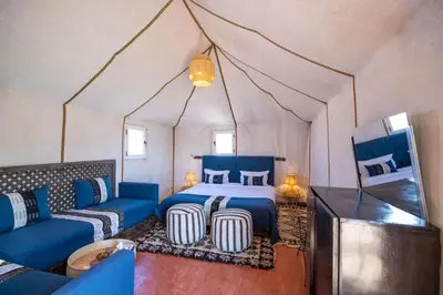 a bedroom with a bed and a couch in a tent at SAHARENA Camp in Merzouga