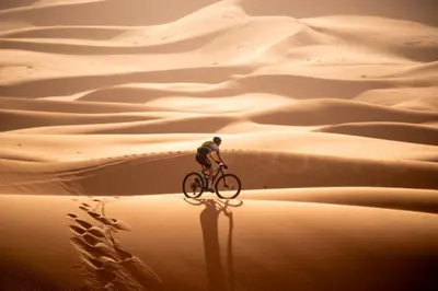 a man riding a bike in the desert at SAHARENA Camp in Merzouga