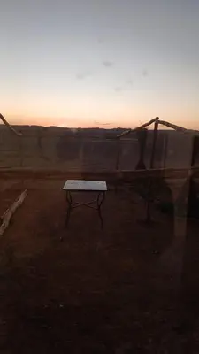 a bench in a field with the sunset in the background at Merzouga Sunshine traditional luxury camp in Merzouga
