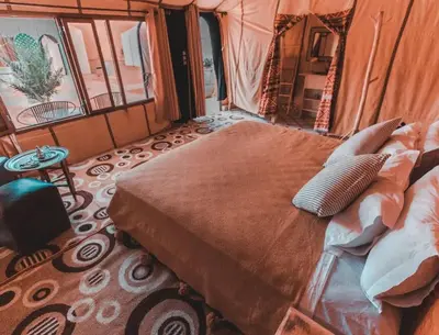 a bedroom with a bed in a tent at Merzouga Sunshine traditional luxury camp in Merzouga
