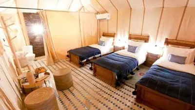 a small room with two beds and a table at Erg Chebbi Luxury Glamping in Khamliya