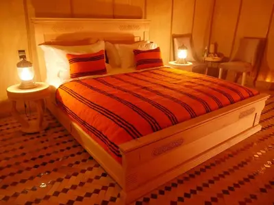 a bedroom with a large bed with two lights on it at Erg Chebbi Luxury Glamping in Khamliya