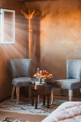 two chairs and a table with a bowl of fruit on it at Erg Chebbi Luxury Glamping in Khamliya