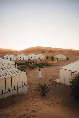 a woman in a white dress standing in the desert at Erg Chebbi Luxury Glamping in Khamliya