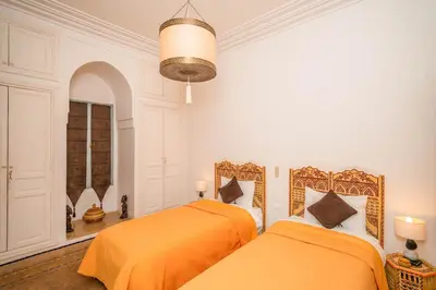 two beds with orange sheets in a white room at Beautiful Boccara villa, 4 suites and private pool in Chaibate