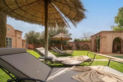 a patio with two chairs and an umbrella at Beautiful Boccara villa, 4 suites and private pool in Chaibate