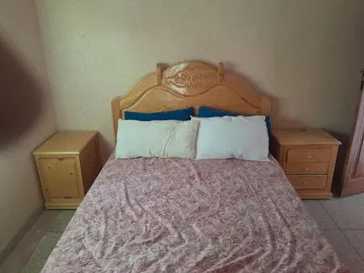 a bedroom with a bed with a wooden headboard and two night stands at maison marocaine atlas in Tinerhir