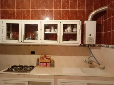 a kitchen with a stove and white cabinets at maison marocaine atlas in Tinerhir