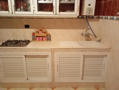 a kitchen with white cabinets and a sink and a stove at maison marocaine atlas in Tinerhir