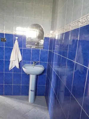 a blue tiled bathroom with a sink and a mirror at maison marocaine atlas in Tinerhir