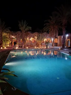 a large swimming pool at night with lights at Hotel oasis merzouga in Merzouga