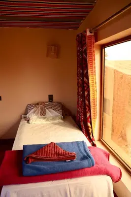 a bedroom with a bed and a window with towels at Rimal Travel Camp in Mhamid