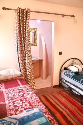 a bedroom with two beds and a rug at Rimal Travel Camp in Mhamid