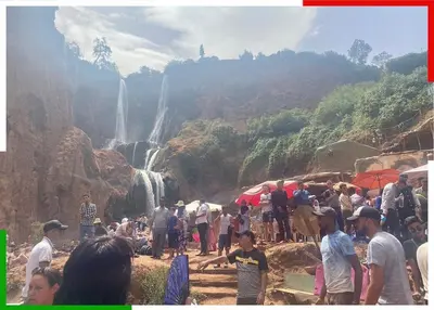 a crowd of people standing in front of a waterfall at Cozy Apartment Near Ouzoud Waterfalls in Azilal