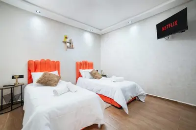 a room with two beds and a tv on the wall at Mina Home 2 in Oulad Akkou