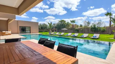 a swimming pool with a wooden table and chairs at Villa Ambre in Marrakech