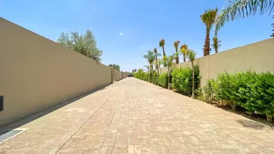 a brick road next to a wall with palm trees at Villa Ambre in Marrakech