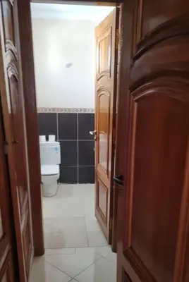 a bathroom with a toilet and a wooden door at Luxurious Accessible Apartment in the Heart of Fes in Fès