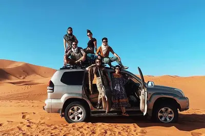 a group of people sitting on the back of a truck in the desert at Andromeda Sahara Camp in Merzouga