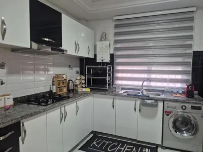 a kitchen with white cabinets and a washing machine at Maison intelligente, idéale pour les familles avec Netflix, parking et ascenseur in Fès